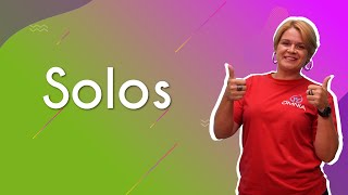 "Solos" escrito sobre fundo verde e rosa ao lado da imagem da professora