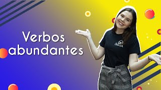 Professora ao lado do texto"Verbos abundantes".