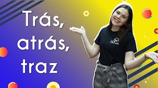 "Trás, atrás, traz" escrito sobre fundo azul e amarelo ao lado da imagem da professora