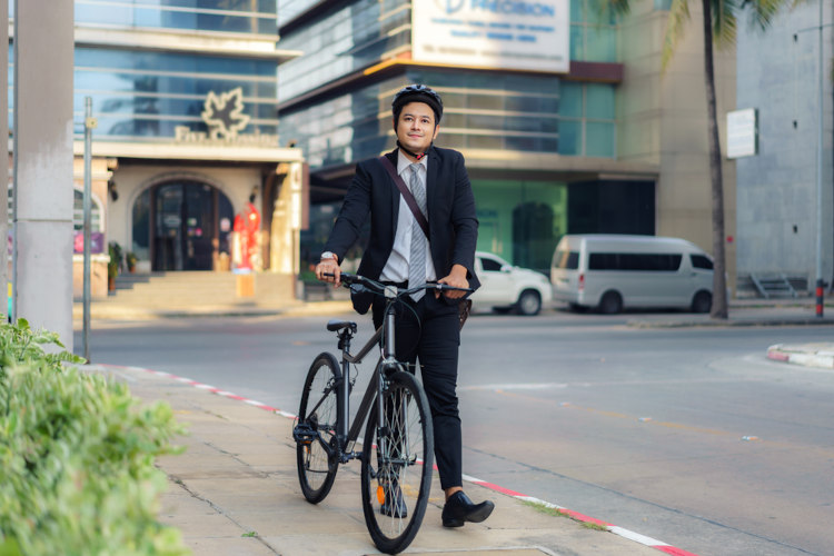  Homem segurando bicicleta em trecho urbano