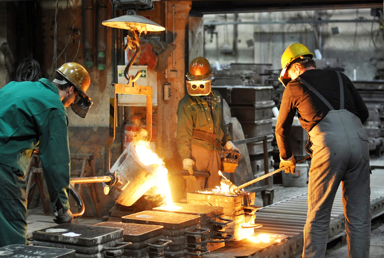 Trabalhadores de uma fundição manipulando metal fundido para a produção de peças.