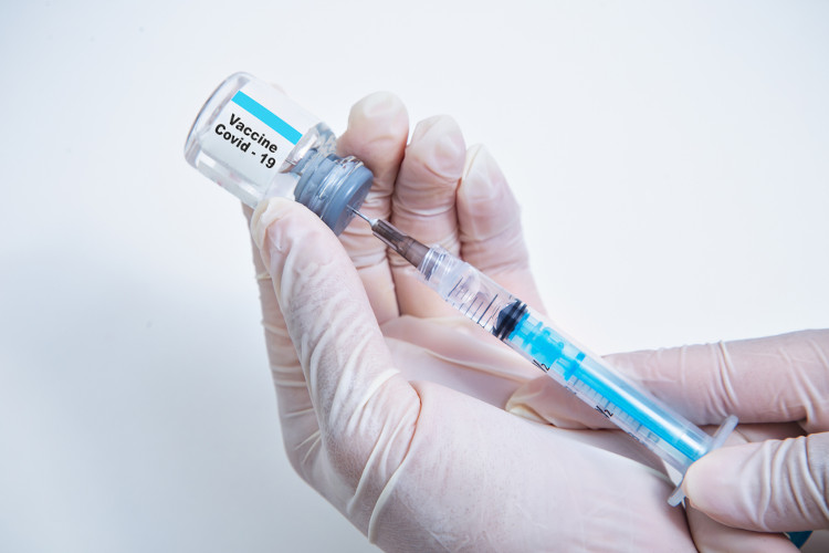 Mãos com luvas seguram dose de vacina e seringa