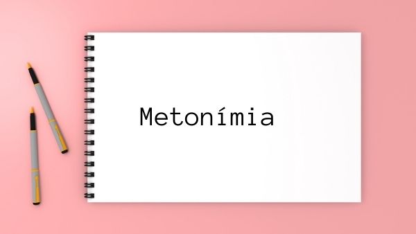 Palavra “metonímia” escrita em caderno sobre fundo rosa.