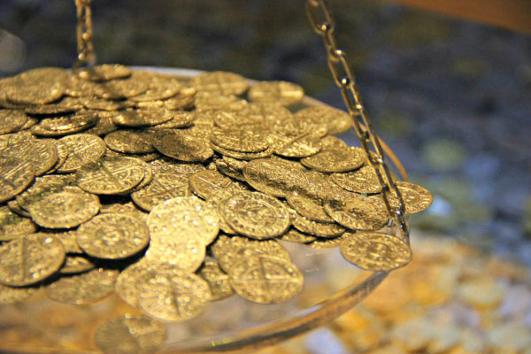 Várias moedas de ouro sendo pesadas em escala.