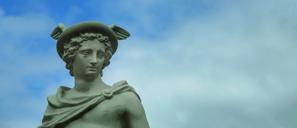 Vista da parte de cima de uma estátua do deus grego Hermes com o céu azul ao fundo.