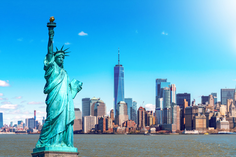 Vista da Estátua da Liberdade com o rio Hudson e a região urbana de Nova Iorque ao fundo.