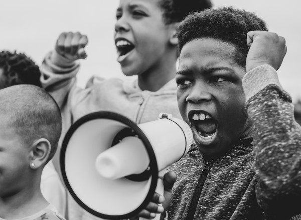Crianças negras diante de um megafone em protesto.