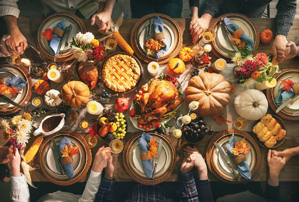 Pessoas reunidas em volta de uma mesa com um banquete servido no Dia de Ação de Graças.