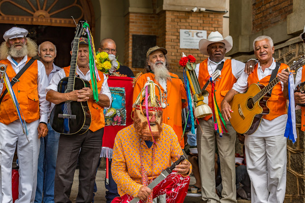 Grupo de homens vestidos a caráter e com instrumentos durante Folia de Reis.
