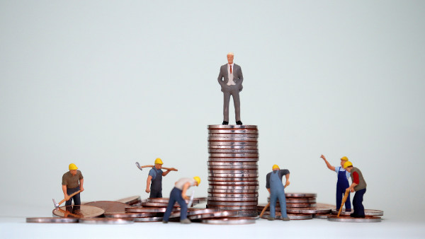 Ilustração de operários construindo uma pilha de moedas e um homem de pé sobre essa pilha representando seu empregador.