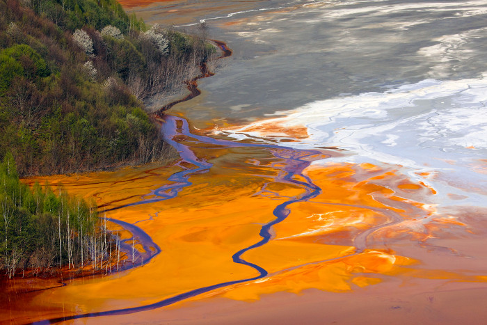 Substâncias poluentes da mineração nas águas de um rio, representando os impactos ambientais dessa atividade.