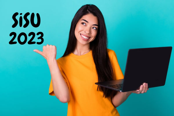 Estudante sorrindo segura computador e aponta para texto SiSU 2023