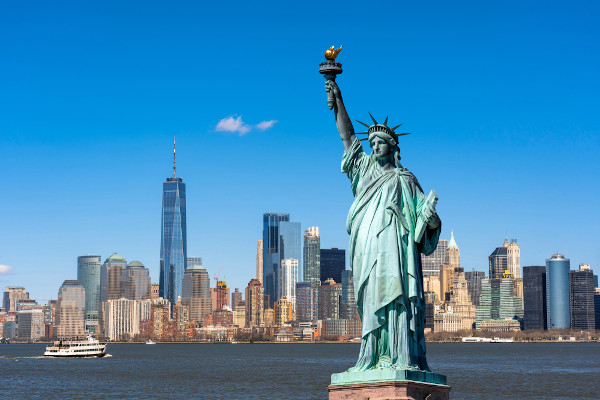 Vista da Estátua da Liberdade com os edifícios da cidade de Nova York e o rio Hudson ao fundo.