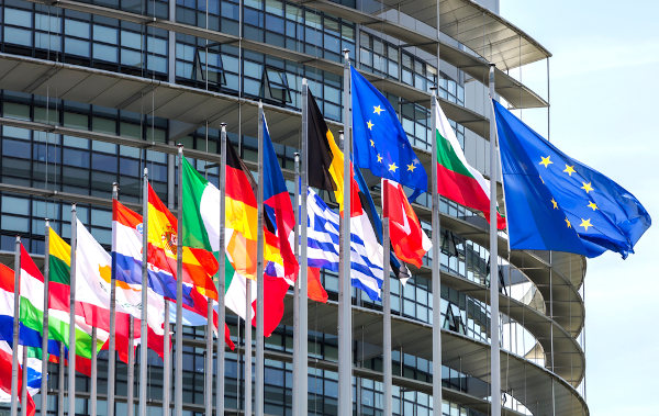 Bandeira da União Europeia hasteada junto às bandeiras dos países que fazem parte desse bloco econômico.