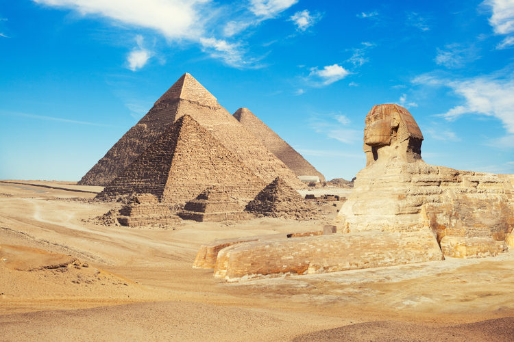 Vista das três Pirâmides de Guizé ao lado da Esfinge, obras de arte egípcias, na paisagem desértica de Cairo, no Egito.