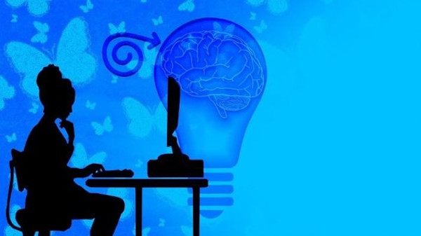 Silhueta de uma mulher sentada na frente de um computador em fundo azul.