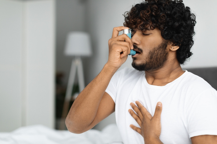 Homem asmático usando uma bombinha broncodilatadora em uma crise de broncoespasmo.