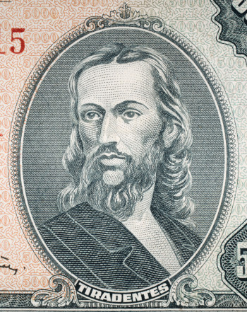 Rosto de Tiradentes com cabelos e barba longos ilustrando uma cédula de cruzeiro, antiga moeda brasileira.