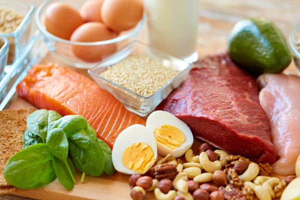 Alimentos ricos em proteínas dispostos sobre uma mesa de madeira.