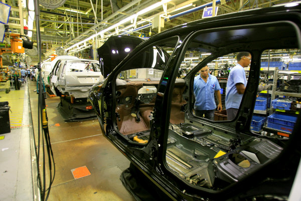 Pessoas trabalhando em uma indústria automobilística, um exemplo do processo de desconcentração industrial no Brasil.