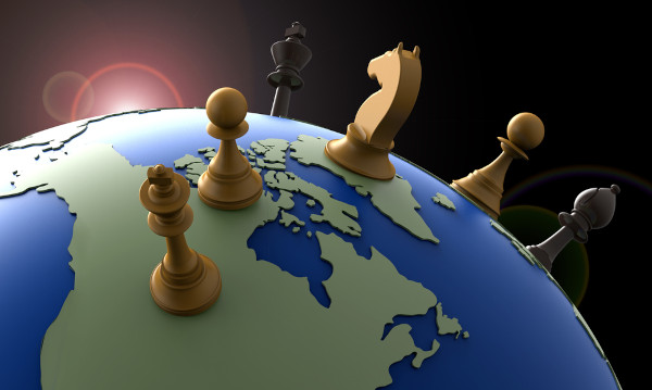 Peças de xadrez sobre globo terrestre em alusão à nova ordem mundial.
