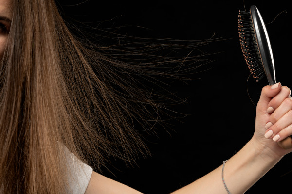 Mulher penteando o cabelo e provocando um processo de eletrização por atrito, um dos processos de eletrização.