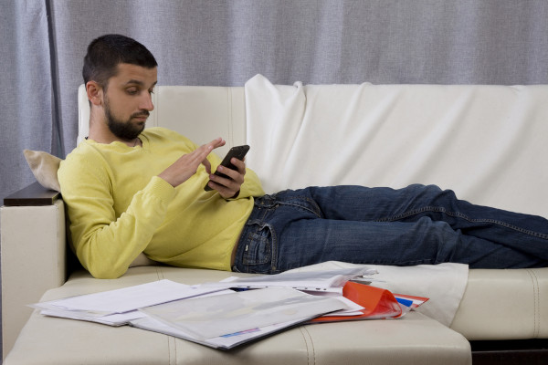 Homem deitado em sofá segurando celular, em texto sobre modernidade líquida.