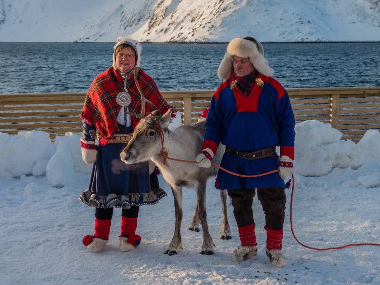 Casal do povo originário sami segurando uma rena.