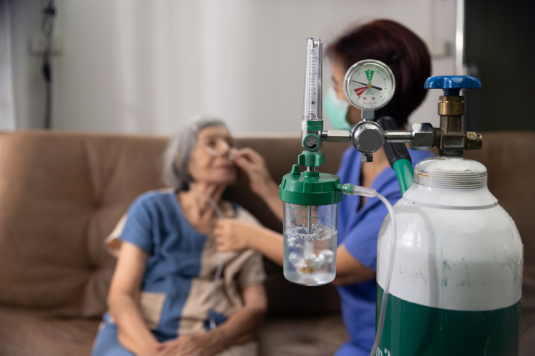 Enfermeira colocando aparelho respiratório em paciente, uma aplicação do calcogênio oxigênio.