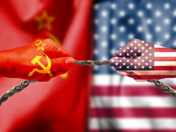 Duas mãos pintadas com cores soviéticas e estadunidenses, puxando uma corda, em alusão à Guerra Fria.