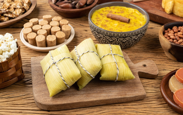 Várias comidas típicas de Festa Junina sobre uma mesa de madeira.