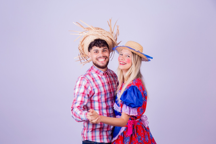 Casal vestindo roupas típicas da quadrilha, a principal dança da Festa Junina.