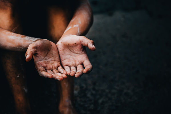 Pessoa em situação de vulnerabilidade com as mãos estendidas, uma alusão à fome no mundo.