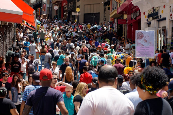 Pessoas diversas na Avenida 25 de Março, em São Paulo, uma alusão à população do Brasil.