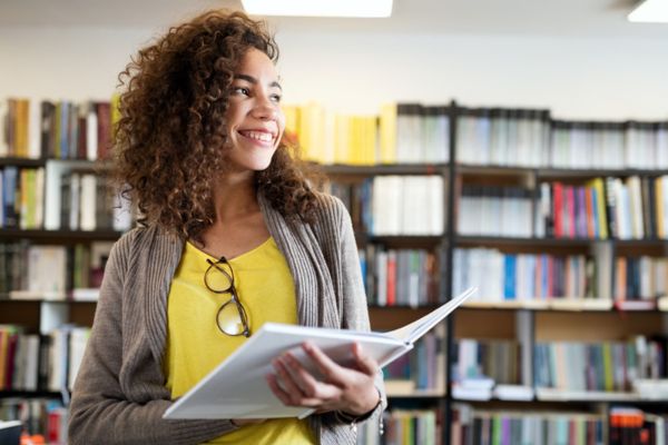 estudante sorrindo com biblioteca ao fundo